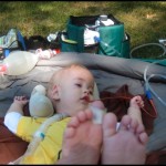 Lucas chills in the grass with his props.  Travelling with Lucas means hours of preparation and packing to bring along the required equipment, chargers, backups, etc.